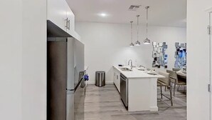 Een moderne keuken met een centraal eiland, roestvrijstalen apparatuur en hanglampen.