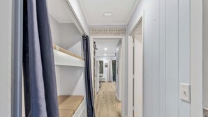 A narrow hallway with bunk beds on one side and a door on the other. - Seaside Sanctuary - Villa Steps from Beach (Hilton Head Island)