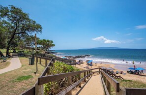 A beach with wooden walkways, benches, and umbrellas.