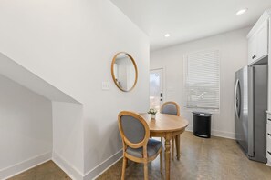 Cozinha moderna com mesa de jantar, cadeiras, geladeira e janela com persianas.