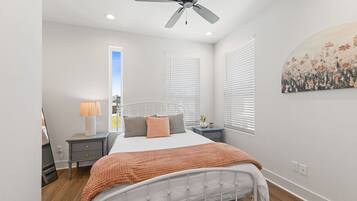 A bedroom with a bed, bedside tables, a ceiling fan, and a window with blinds.