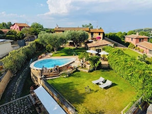 A residential property with a swimming pool, a grassy yard, and a small garden area.