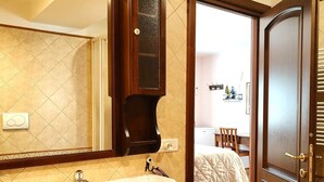 A bathroom with a large mirror, a sink, and a door leading to a bedroom. - La Valle Dei Casali B&B (Rome)