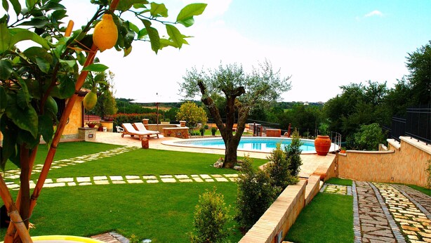 A backyard with a swimming pool, a lawn, and a stone pathway. - La Valle Dei Casali B&B (Rome)
