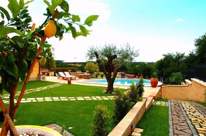 A backyard with a swimming pool, a lawn, and a stone pathway. - La Valle Dei Casali B&B (Rome)