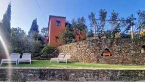Piscina com muro de pedra e espreguiçadeiras.