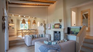 Uma sala de estar com sofá, lareira, televisão e escada.