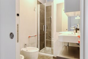A modern bathroom with a glass-enclosed shower, a sink, and a toilet. - Stylish 2BR flat next to Navigli (Milan)