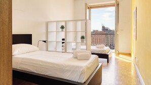 A modern hotel room with a large bed, a small desk, a window with a city view, and a balcony. - Stylish 2BR flat next to Navigli (Milan)