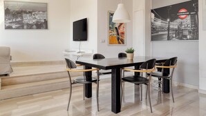 A modern dining area with a black table, four chairs, and a hanging white pendant light. - Stylish 2BR flat next to Navigli (Milan)