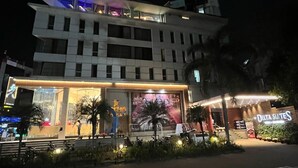Un hotel moderno con una entrada destacada, un balcón visible y un letrero que dice 'Delta Suites'.