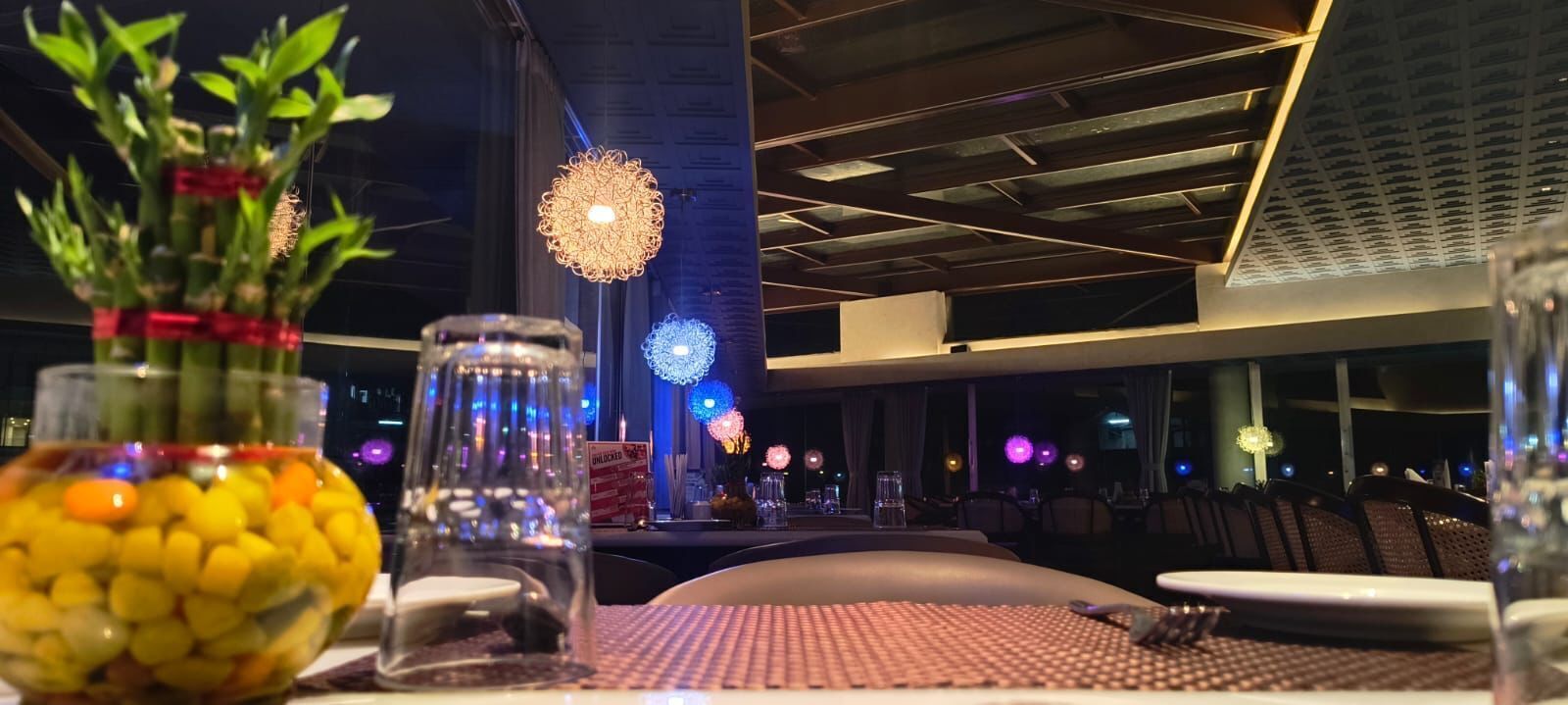 Ein Restaurantinnenraum mit gedecktem Tisch, dekorativen Gläsern und einer hängenden Leuchte.