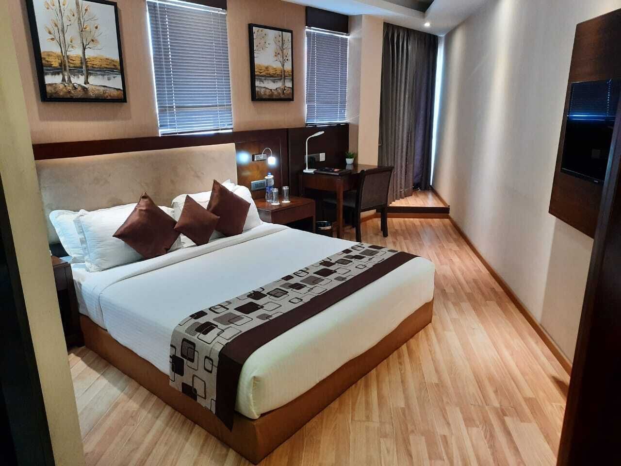 Habitación de hotel con una cama grande, un escritorio, una silla y un televisor.