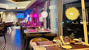 Un restaurante moderno con techo alto, diseño geométrico en el techo y piso estampado.