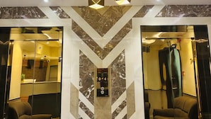 Un interior moderno con paredes de diseño geométrico, un ascensor central e iluminación contemporánea.