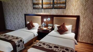 A hotel room with two beds, a nightstand with a lamp, and a wall-mounted picture.