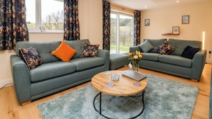 A modern living room with two grey sofas, a round wooden coffee table, and a blue shaggy rug. - Hideaway (Torrington)