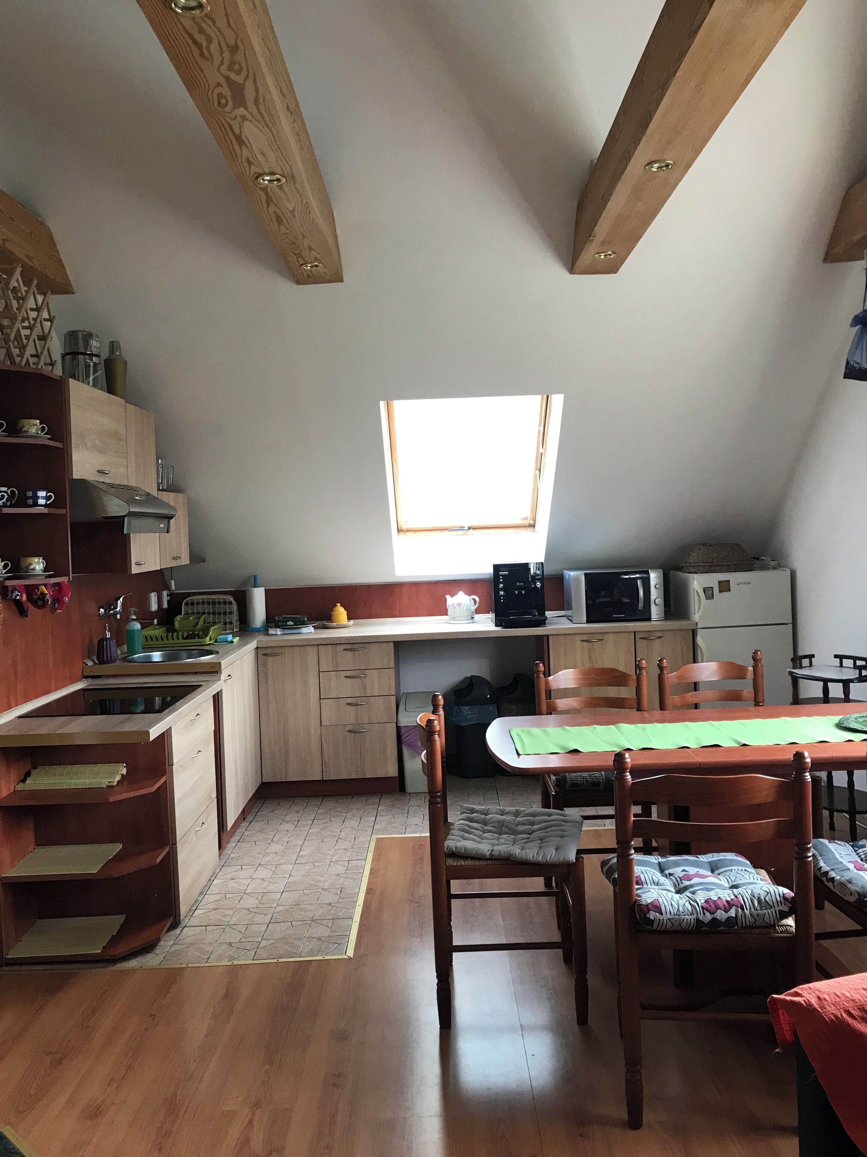 A compact kitchen with wooden cabinets, a dining table, and a small window.