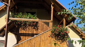 A wooden staircase leading to a balcony with hanging flower baskets.