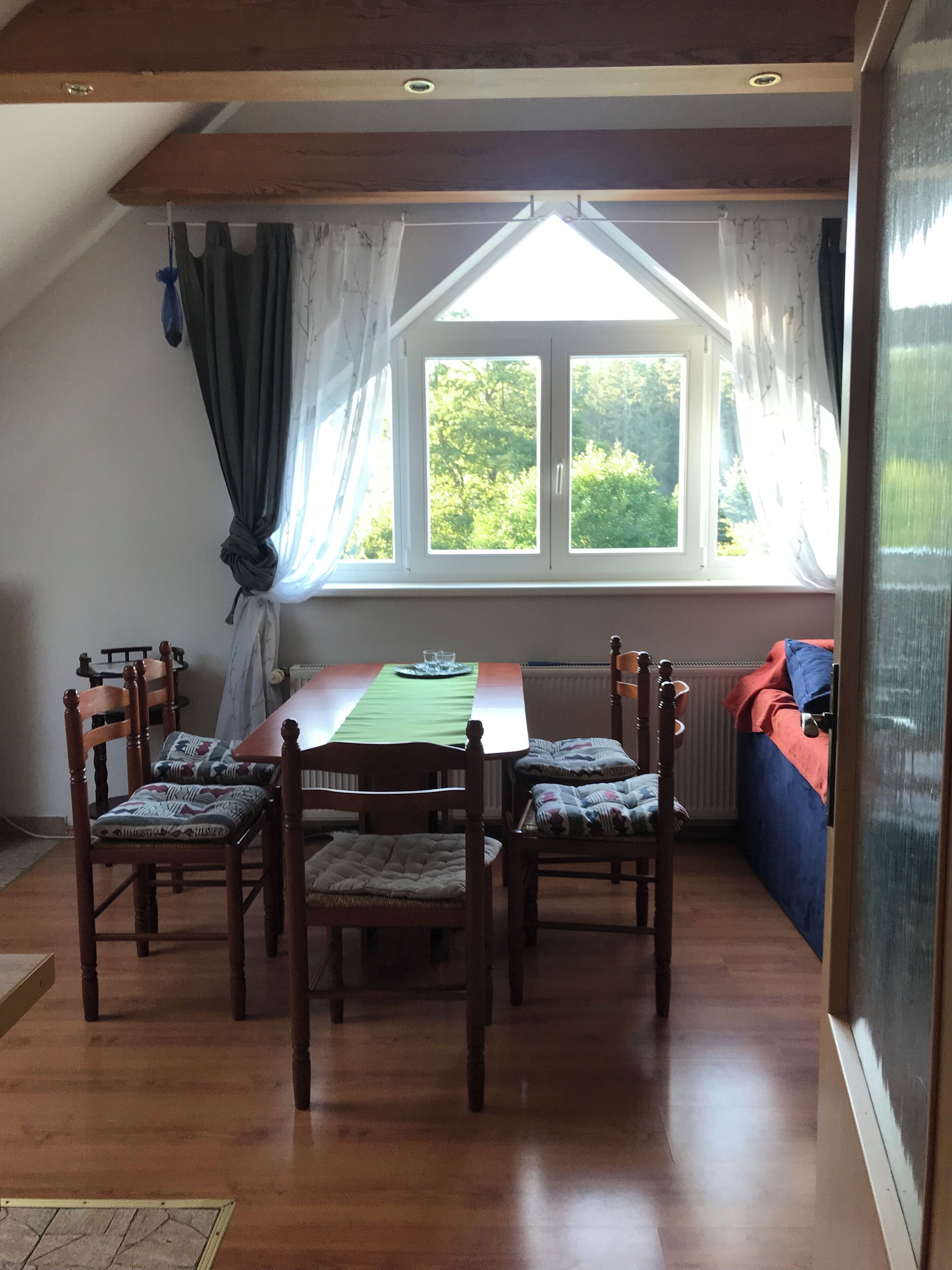 Un comedor con una mesa y sillas, una ventana con cortinas y vistas al exterior.
