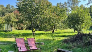 A serene outdoor setting with two striped lounge chairs and a small stream.
