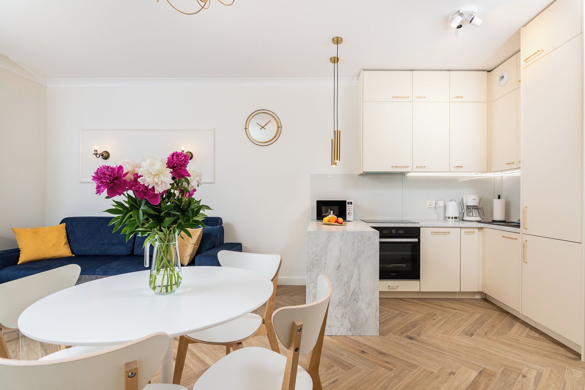 A modern kitchen with white cabinets, a marble countertop, and a built-in oven.