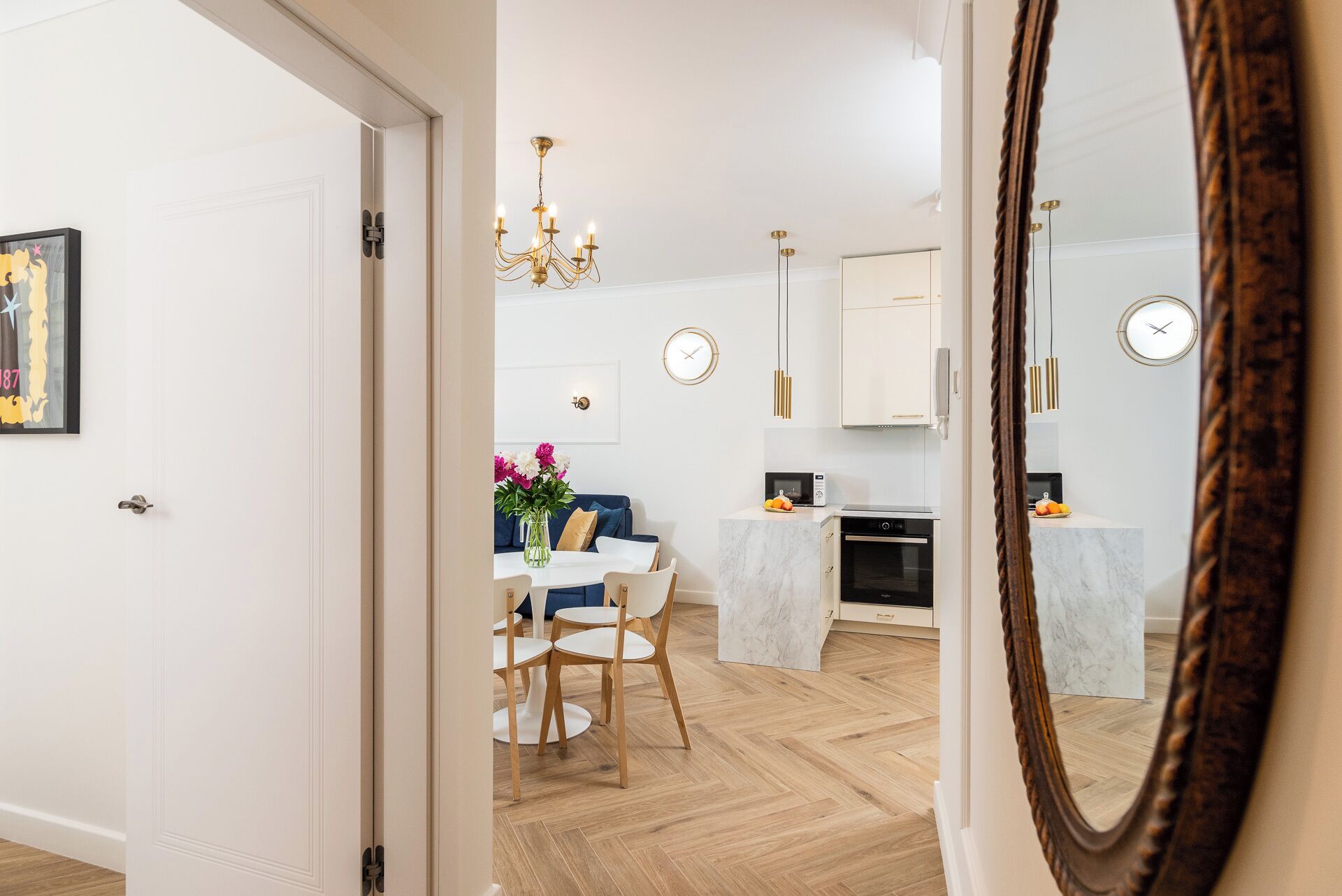 A modern kitchen with white cabinets, a marble countertop, and a built-in oven.