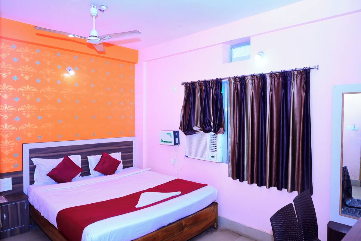 Habitación de hotel con una cama, ventilador de techo, aire acondicionado y una ventana con cortinas.