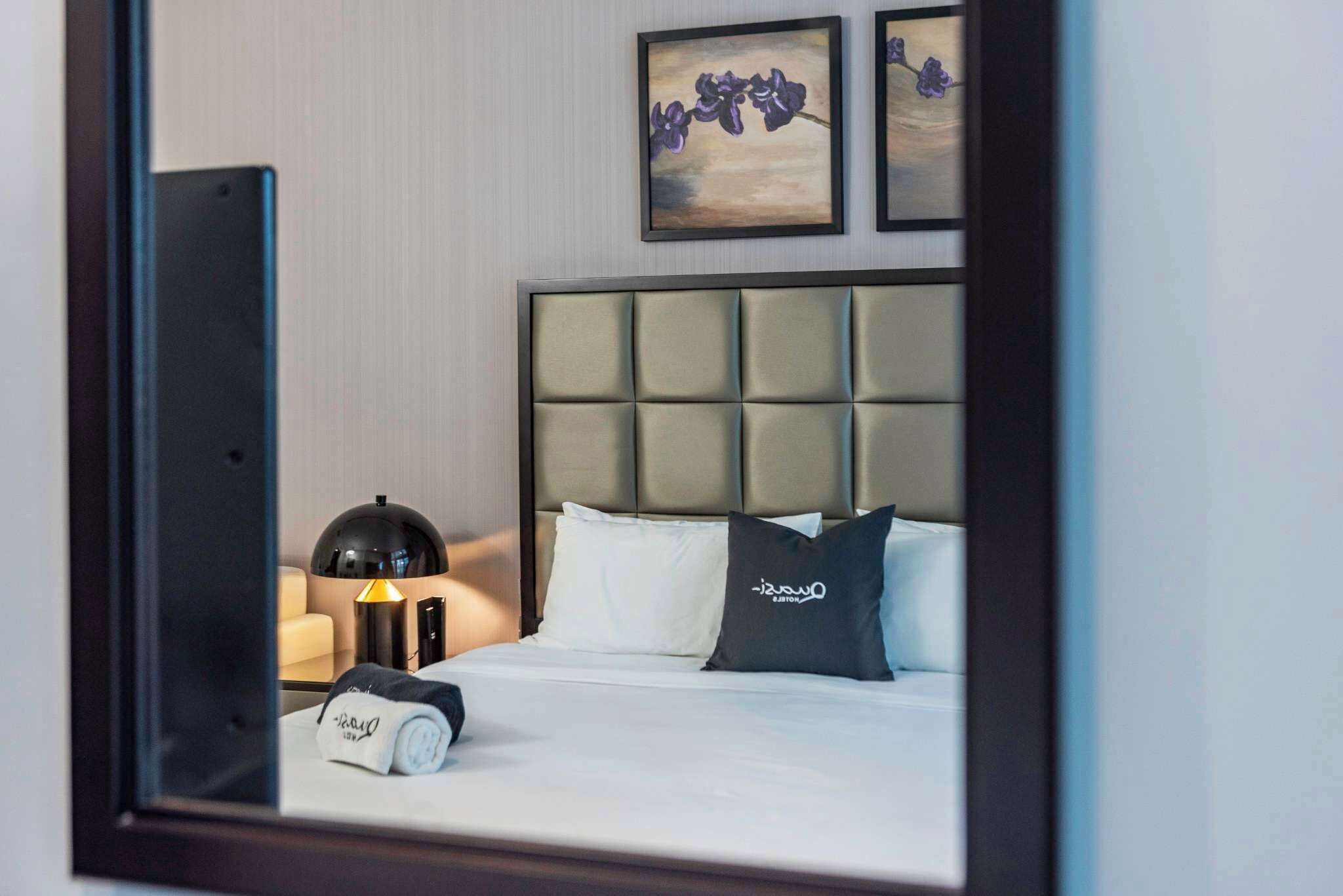 Inviting bedroom with soft lighting, plush bedding & elegant wall art, pure comfort.