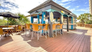 Une terrasse en bois avec des sièges d’extérieur et une petite construction surmontée d’un toit bleu.