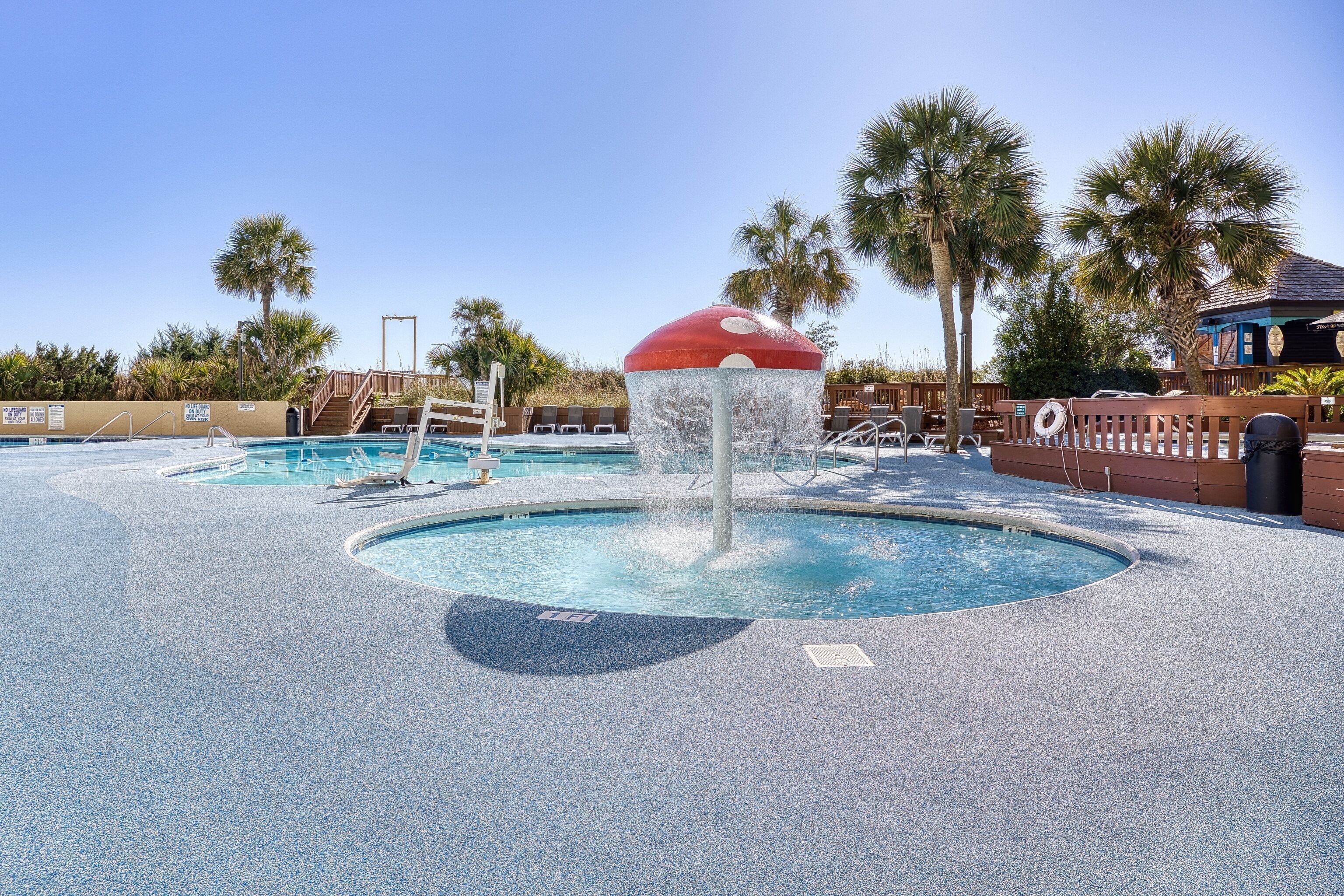 A pool area with a central water feature and surrounding palm trees.