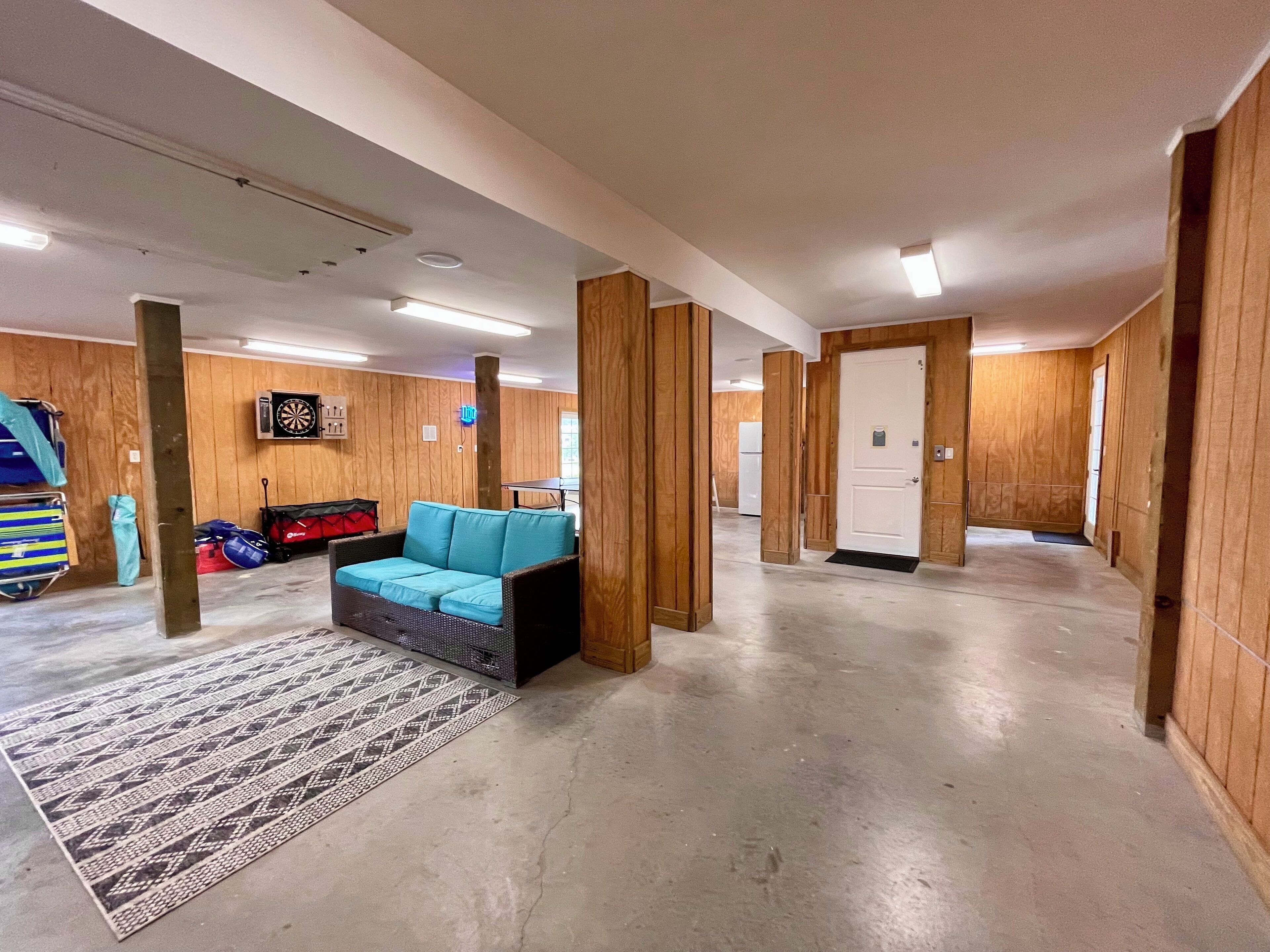 A spacious indoor area with a blue sofa, a patterned rug, wooden walls, and a door.