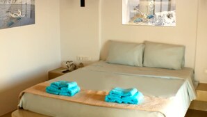 Een slaapkamer met een bed, twee kussens, een nachtkastje, een wandlamp en een raam met uitzicht op een besneeerd landschap.