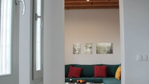 Un salón moderno con un sofá verde, cojines rojos y amarillos, y una mesita de centro con frutas.