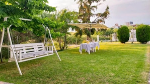 Un patio con una hamaca, una mesa techada y césped.