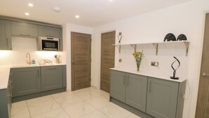 A modern kitchen with grey cabinets, a white countertop, and a tiled floor. - The Annex (Ripley)