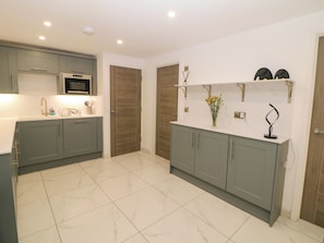A modern kitchen with grey cabinets, a white countertop, and a tiled floor. - The Annex (Ripley)