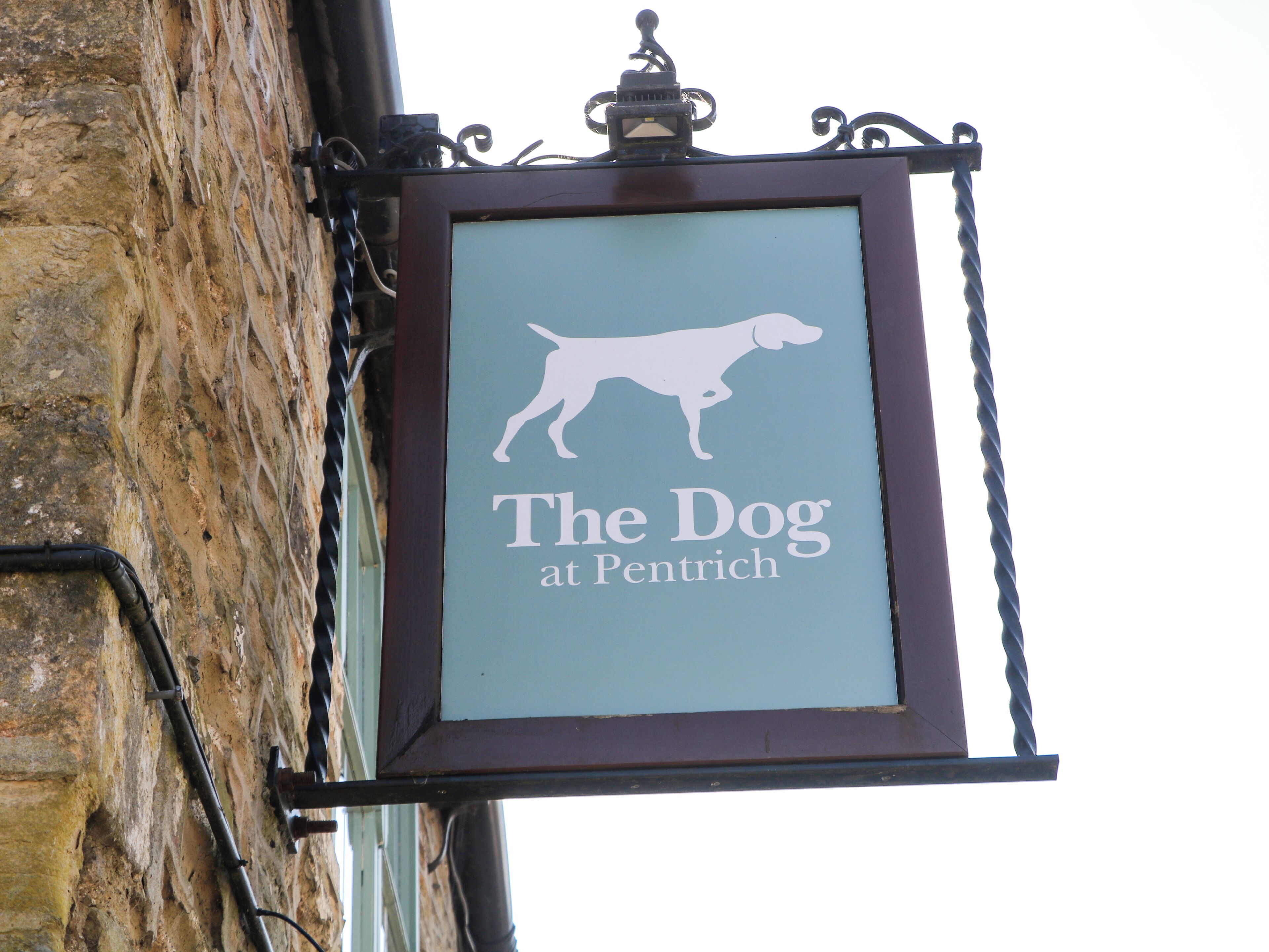 Um letreiro pendurado com silhueta de cachorro e o texto 'The Dog at Pentrich'.