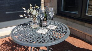 A round metal table with a bottle of champagne and two glasses on it. - The Annex (Ripley)