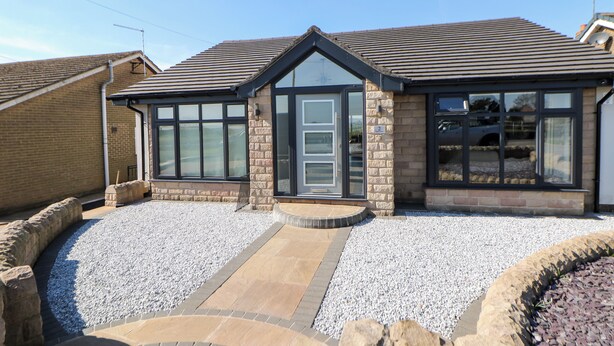 A modern house with a stone facade, large windows, and a gravel driveway. - The Annex (Ripley)