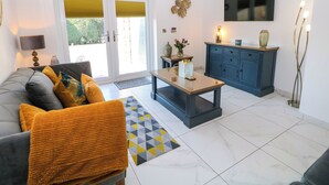 A modern living room with a sofa, coffee table, and a TV mounted on the wall. - The Annex (Ripley)