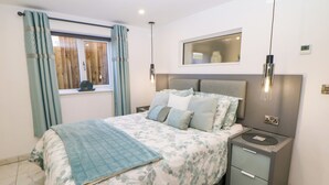 A bedroom with a bed, nightstands, a mirror, and a window with curtains. - The Annex (Ripley)