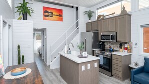 Une cuisine moderne dotée d’un îlot central, d’appareils électroménagers intégrés et offrant une vue sur l’espace de vie.