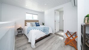 Une chambre à coucher avec un lit, une petite table de chevet, une fenêtre et une porte.