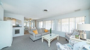 A living room with a grey sofa, a glass coffee table, and a patterned armchair. - River Love, private dock Moovalya Keys (Parker)