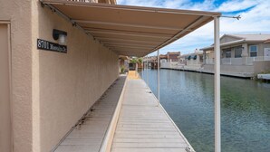 A covered walkway adjacent to a canal, with a building marked "8701 Moovalya Dr." - River Love, private dock Moovalya Keys (Parker)