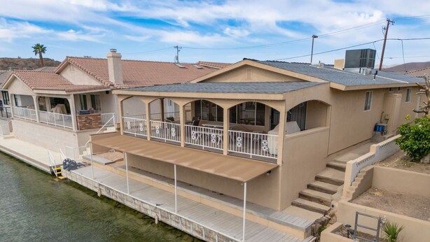 A waterfront house with a covered deck, a second-story balcony, and a small boat docked at the front. - River Love, private dock Moovalya Keys (Parker)