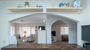 A living room with a fireplace, a television, and a kitchen area with a stove. - River Love, private dock Moovalya Keys (Parker)