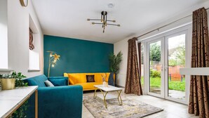 A modern living room with teal and yellow sofas, a white coffee table, and a large window with curtains. - Spacious 4bd 3.5bt - Etihad COOP -Cinema PoolTable (Greater Manchester)