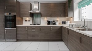 A modern kitchen with dark wood cabinets, stainless steel appliances, and a window with a view. - Spacious 4bd 3.5bt - Etihad COOP -Cinema PoolTable (Greater Manchester)